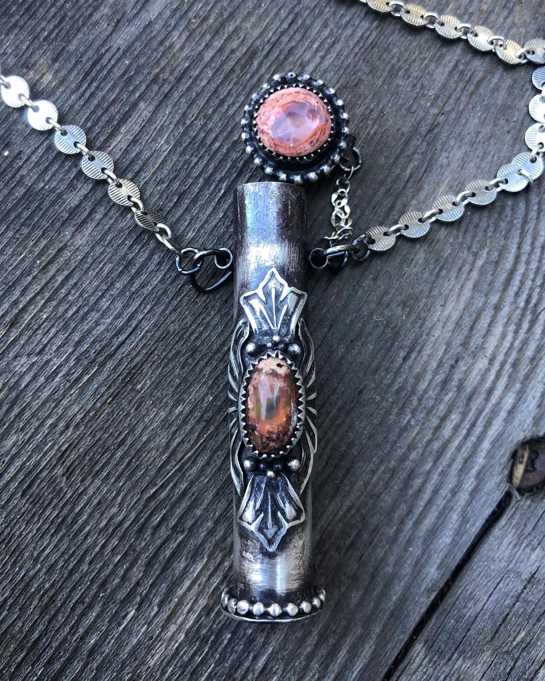 A sterling Fire Opal MedicineKeeper pendant with pink opal stones on weathered wood